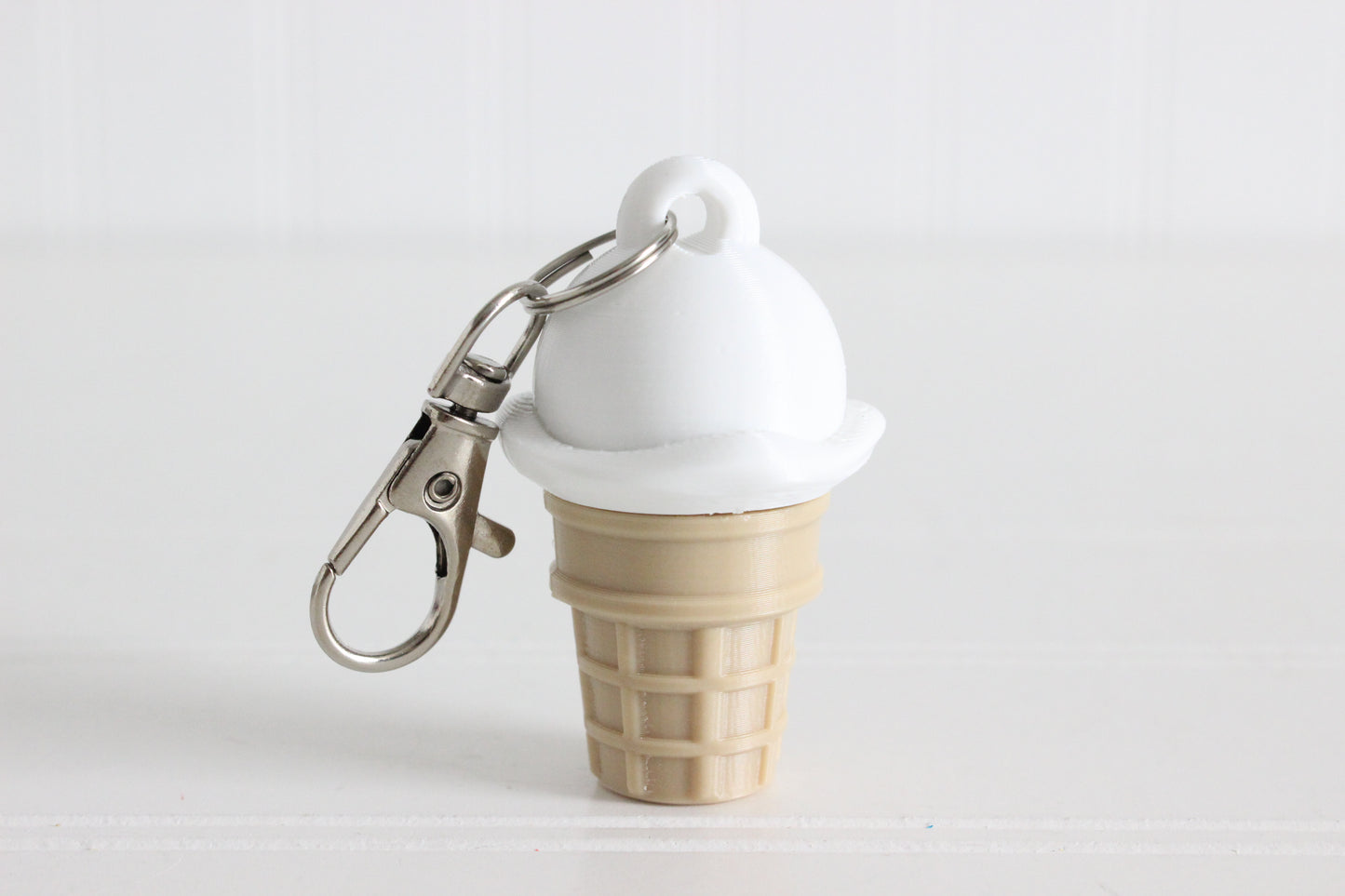 3D-printed vanilla ice cream cone keychain with a metal key ring on a white background.