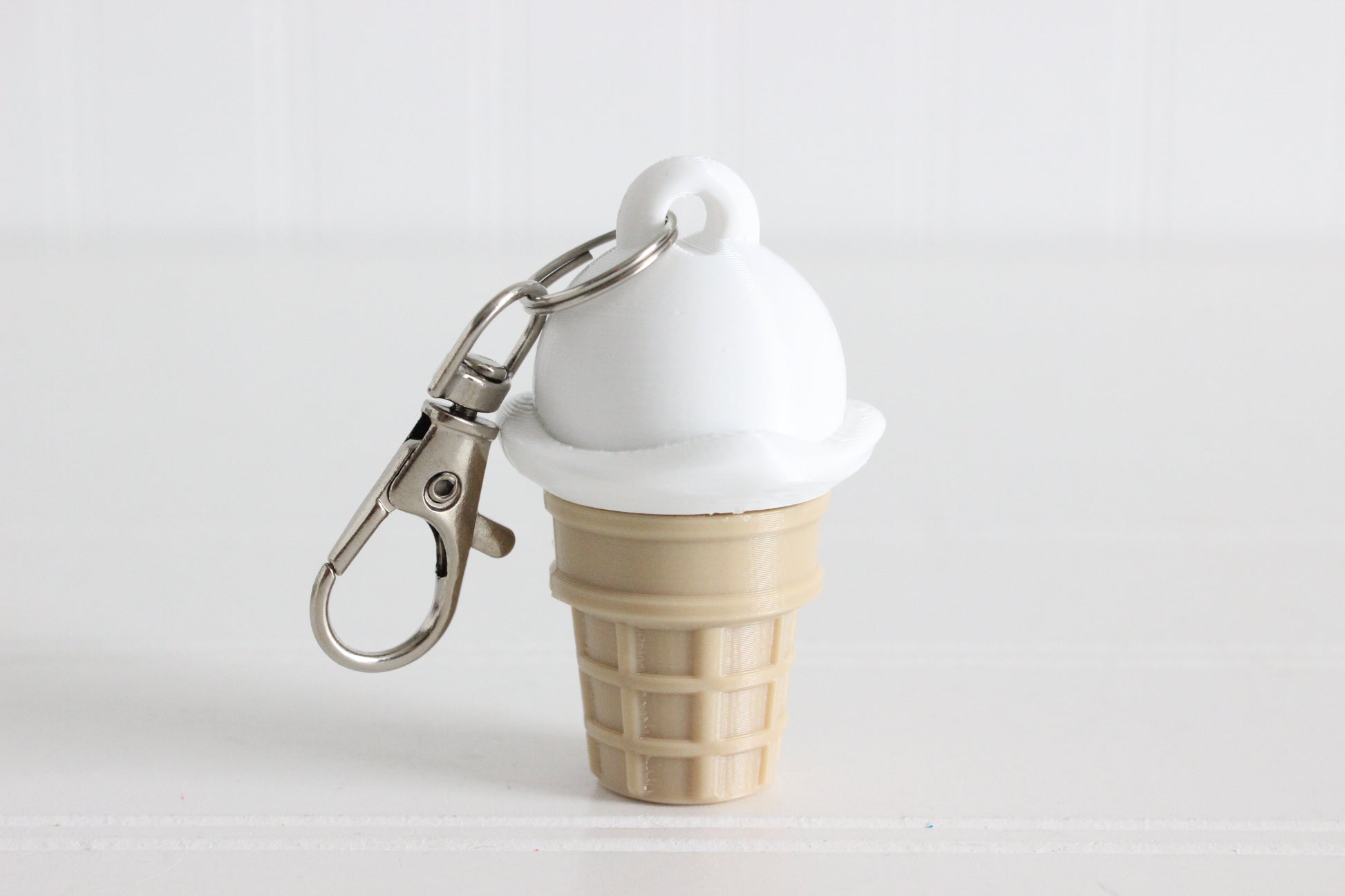 3D-printed vanilla ice cream cone keychain with a metal key ring on a white background.