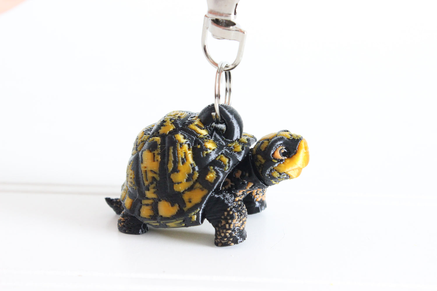 3D-printed brown-and-gold box turtle keychain with a silver swivel quick-clip on a white background.